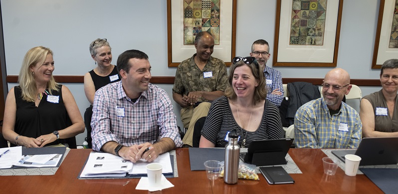 A photo of several people sitting at a table, and several more people sitting behind them, from the AHA's 2019 department chairs workshop.